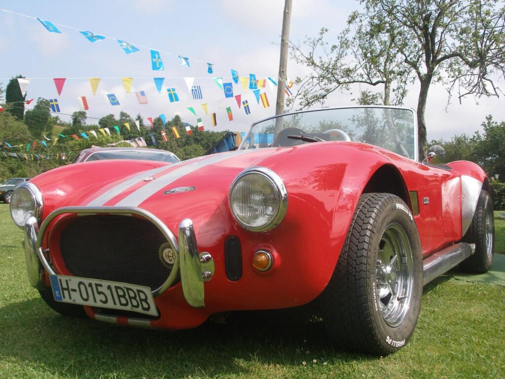 Primer plano de un AC Cobra rojo con rayas de competición blancas, ideal para el alquiler en eventos corporativos y rodajes.