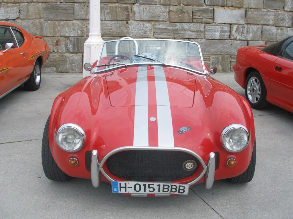 Primer plano de un AC Cobra rojo con rayas de competición blancas, ideal para el alquiler en eventos corporativos y rodajes.