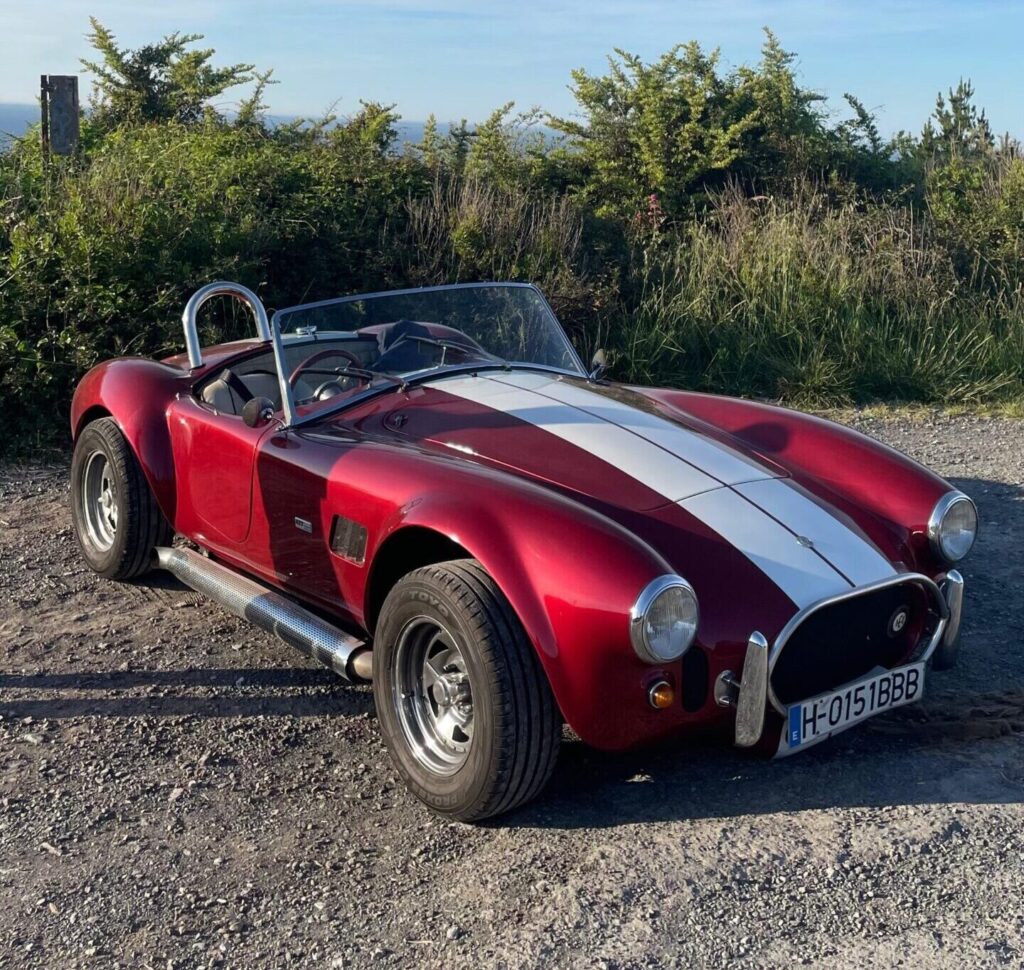 AC Cobra rojo con rayas de competición blancas.