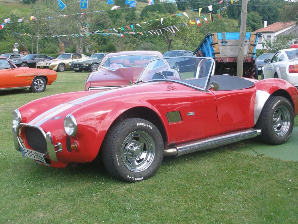 Primer plano de un AC Cobra rojo con rayas de competición blancas, ideal para el alquiler en eventos corporativos y rodajes.