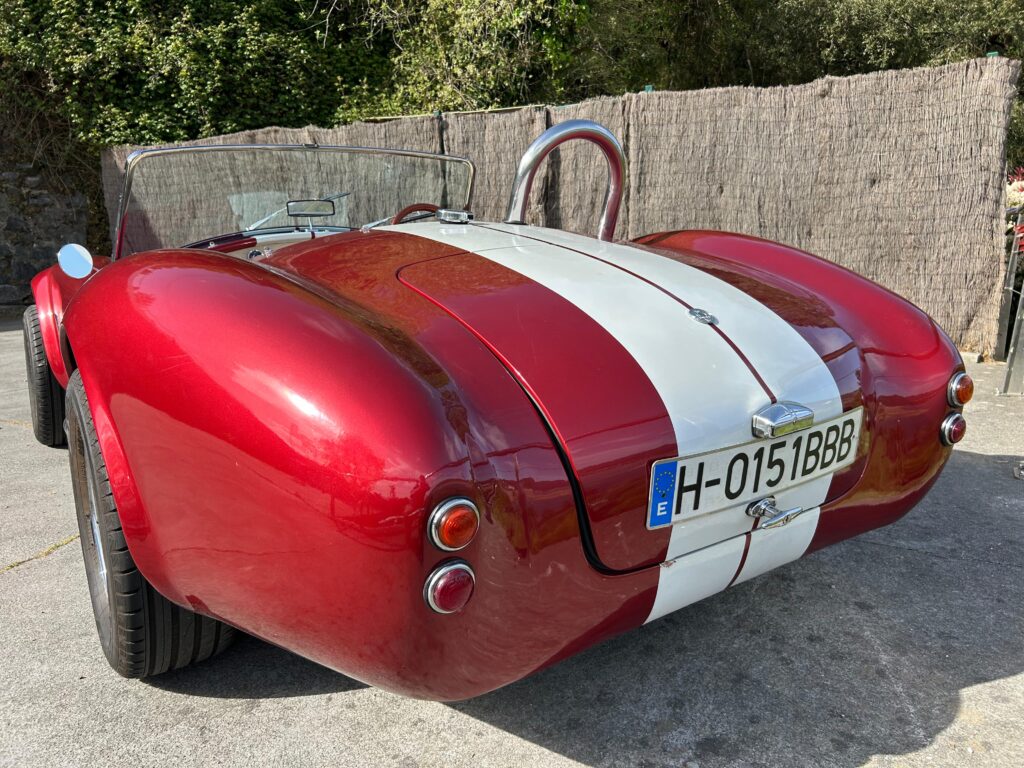 Primer plano de un AC Cobra rojo con rayas de competición blancas, ideal para el alquiler en eventos corporativos y rodajes. Disponible en Bilbao y País Vasco.