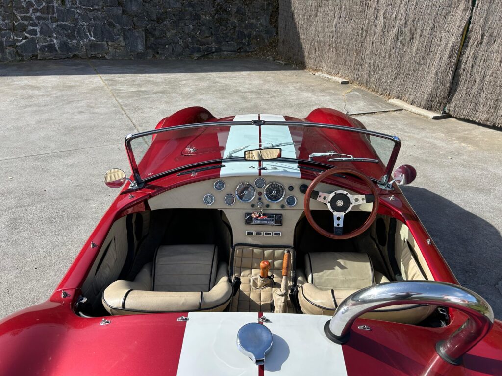 Primer plano de un AC Cobra rojo con rayas de competición blancas, ideal para el alquiler en eventos corporativos y rodajes. Disponible en Bilbao y País Vasco.