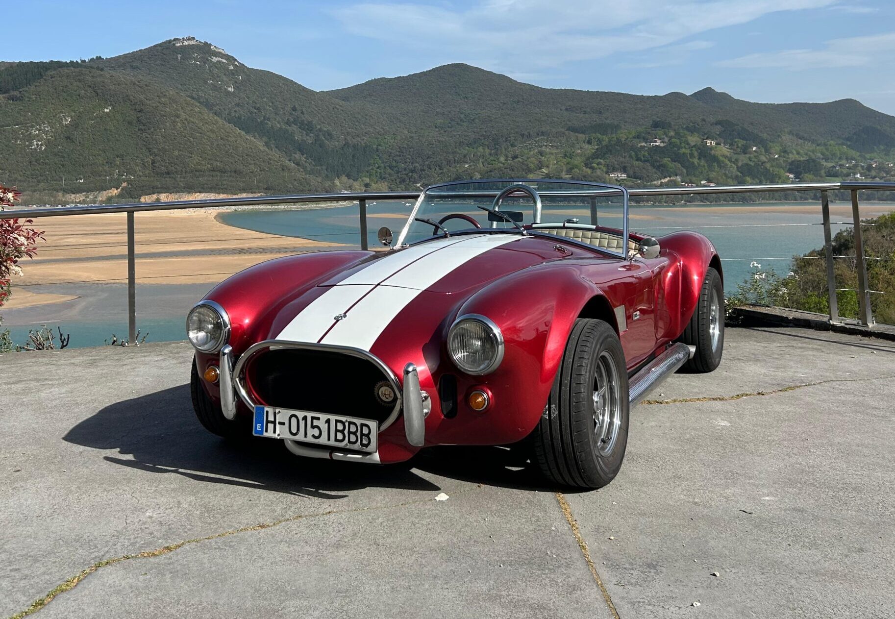 Primer plano de un AC Cobra rojo con rayas de competición blancas disponible para bodas en Bilbao y País Vasco. Colección clásicos para eventos